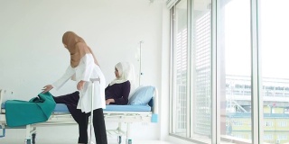穆斯林妇女医生照顾穆斯林妇女。女医生用轮椅把病人送到床上