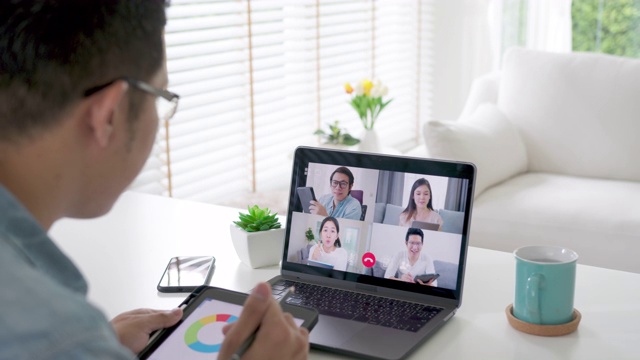 缩小后视:商人在视频会议中交谈。亚洲团队使用笔记本电脑和平板电脑进行在线视频会议。在家工作，远程工作和在家自我隔离