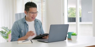 慢动作跟踪镜头:商人在视频会议中讲话。亚洲团队使用笔记本电脑和平板电脑进行在线视频会议。在家工作，远程工作和自我隔离。