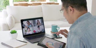 缩小后视:商人在视频会议中交谈。亚洲团队使用笔记本电脑和平板电脑进行在线视频会议。在家工作，远程工作和在家自我隔离