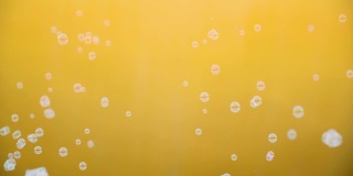 白色的肥皂泡在黄色的背景上飘动