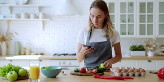 为有机沙拉准备蔬菜的女性可以看看智能手机