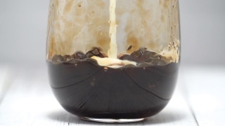 泡奶茶，将牛奶和茶倒入红糖图案的水杯中，放置在白色的木桌背景上视频素材模板下载