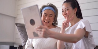 亚洲资深女性和女儿在家里通过平板电脑进行视频会议