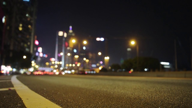 汽车在香港的道路上快速移动与模糊的散景效果的建筑灯光在夜间-地面水平拍摄