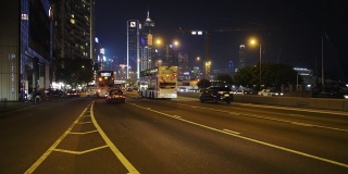 车辆行驶在繁忙的道路上在香港的夜晚与风景优美的高楼大厦的背景-广角镜头