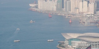 白天在香港会议展览中心和天际线上的渡轮航行维多利亚港。-高角度拍摄