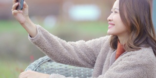 在秋天，微笑的亚洲女性游客用智能手机拍下了日本乡村阴云密布的山景。美丽的女士放松和享受秋天假期在日本旅游