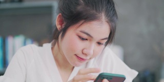 亚洲女性自由职业者使用智能手机在家里上网。