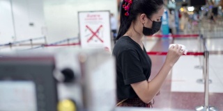 年轻的亚洲女性从机场航站楼的航空公司值机柜台领取机票、登机牌、新冠肺炎疫情、新常态旅行社交距离、航空行业