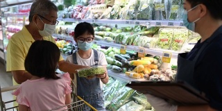 一位亚洲华人中年女性零售助理，建议并帮助一个家庭从超市的冷藏区选择蔬菜