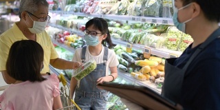 一位亚洲华人中年女性零售助理，建议并帮助一个家庭从超市的冷藏区选择蔬菜