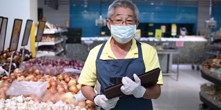 一名亚洲华人高级男子，超市店主，零售助理，戴着口罩