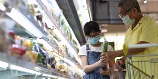 一个亚洲华人家庭周末在超市的冷藏区购买蔬菜