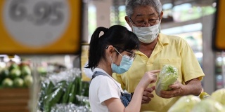 一个活跃的亚洲华人老人和他的孙女在购物和挑选白菜