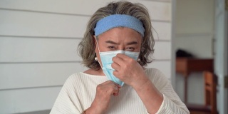一名亚洲老年妇女戴着口罩，以防止感染Covid - 19病毒。
