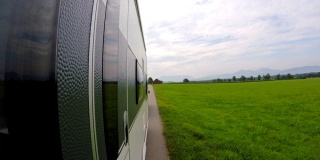 一辆车拖着一辆大篷车行驶在乡间的巴伐利亚路上