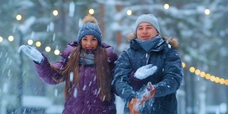 一对穿着夹克和帽子的有趣夫妇在冬天的公园里扔雪