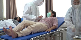 一群身穿防护服的亚洲医生正在医院隔离病房的病床上检查和治疗因冠状病毒或covid - 19咳嗽的患者。流感爆发