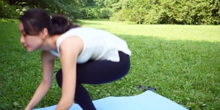 瑜伽教练坐在运动垫上，在公园里冥想