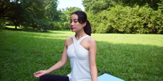 瑜伽教练坐在运动垫上，在公园里冥想