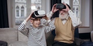 慢动作的顽皮友好的微笑胡子老人和他十几岁的孙子玩电子游戏用特殊的3d眼镜在家里
