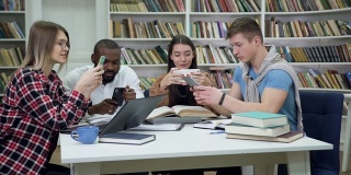 在图书馆准备考试的间隙，迷人的、快乐的、年轻的、多种族的朋友们在玩手机