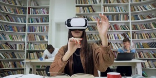 迷人的明亮自信的现代女孩戴着增强现实眼镜坐在图书馆里，在虚拟屏幕上看书的慢动作