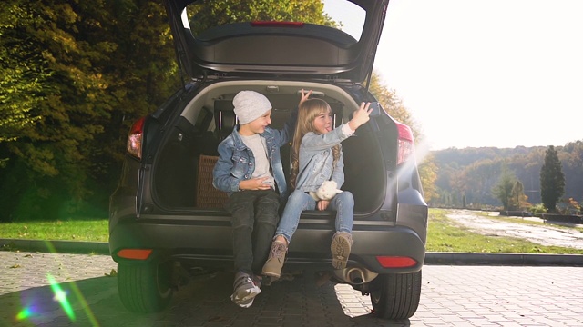 青少年男孩女孩坐在汽车后备箱自拍