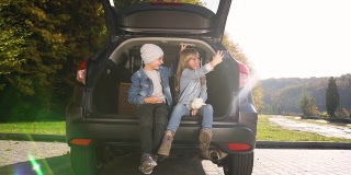 青少年男孩女孩坐在汽车后备箱自拍