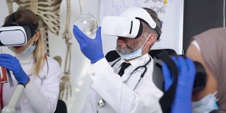 可敬的灰胡子医生使用虚拟现实耳机学习瓶中的化学物质