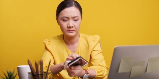 亚洲女人清洁智能手机和笔记本电脑在黄色的背景