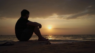 亚洲男子沮丧和坐在海滩日落，芭堤雅视频素材模板下载