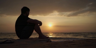 亚洲男子沮丧和坐在海滩日落，芭堤雅