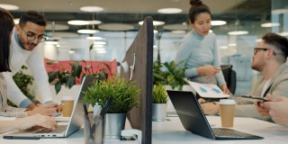 多种族团队在共享工作空间使用笔记本电脑在项目中工作