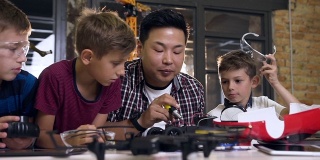亚洲电子工程师与白人学生在现代学校实验室工作和测试模型电动车。科学和技术