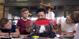 在现代学校的桌子上，年轻的韩国电子工程师和孩子们用螺丝刀拆卸机器人