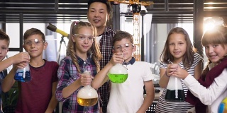 这是韩国科学家教年轻学生做化学实验的照片，孩子们拿着装有液体的烧瓶，液体会引起强烈的蒸发，冒烟