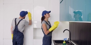 漂亮年轻的清洁公司工人戴着橡胶手套擦拭高科技厨房