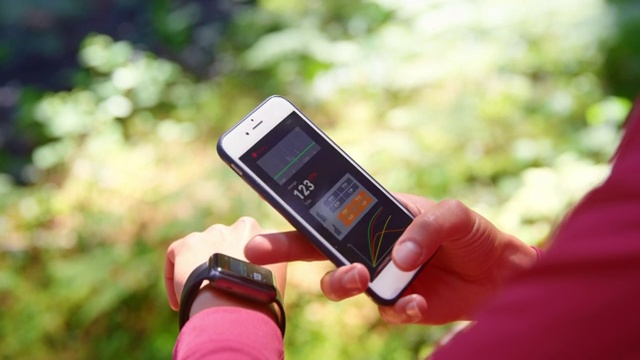 SLO MO女跑步者查看她的手表和智能手机上的数据