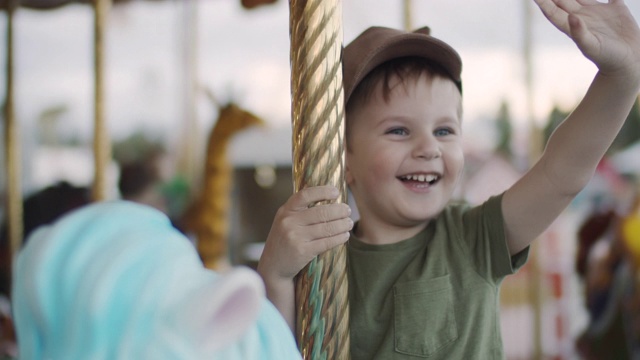可爱的小男孩喜欢在游乐场玩旋转木马