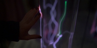 安装在科学博物馆。一个女人的手用发光的气体教管子的慢动作镜头。惰性气体发光。管与发光的等离子体
