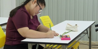 一个患有唐氏综合症的女孩在桌子上专心地画画