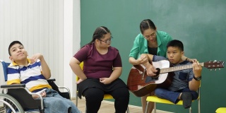 老师在教室里教残疾儿童吉他，非常开心