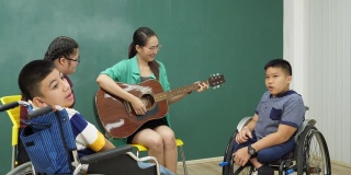 老师在教室里弹吉他陪着残疾儿童，非常开心