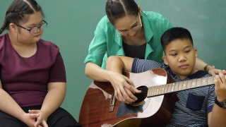 老师在教室里教残疾儿童吉他，非常开心视频素材模板下载