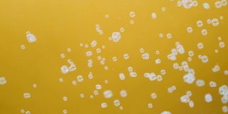 白色的肥皂泡在黄色背景的慢动作中飘动