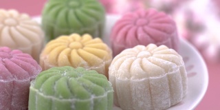 五颜六色的雪皮月饼，甜的雪月饼，传统美味的甜点中秋节在柔和的淡粉色背景