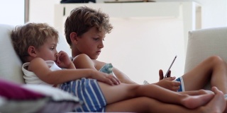 偷拍的孩子们在平板电脑上观看媒体娱乐节目。孩子们在看设备屏幕