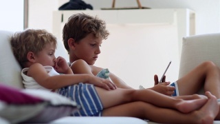 偷拍的孩子们在平板电脑上观看媒体娱乐节目。孩子们在看设备屏幕视频素材模板下载